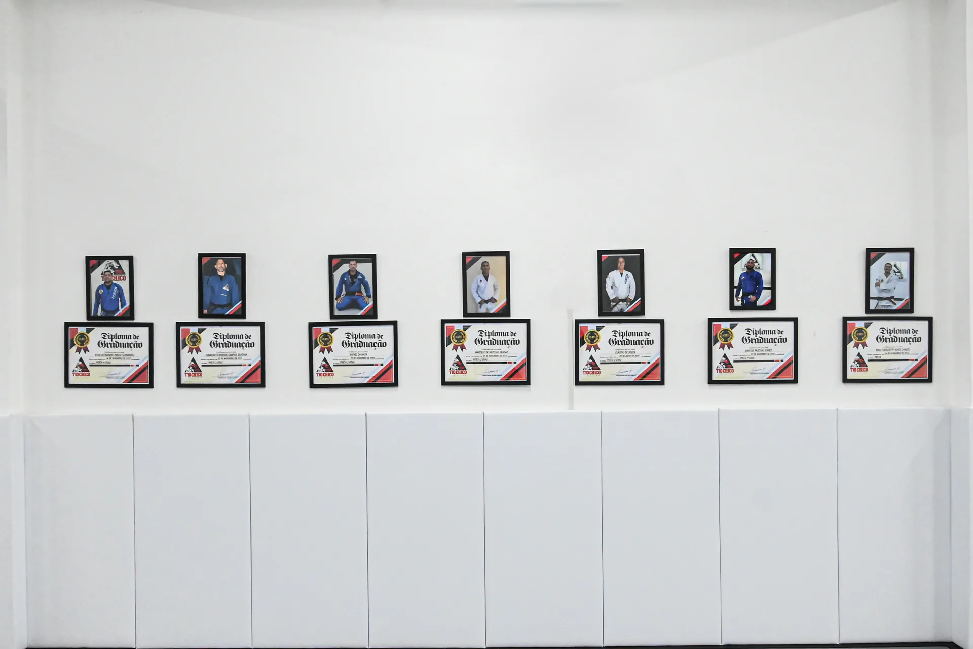 Quadro de graduações com os certificados e retratos dos professores