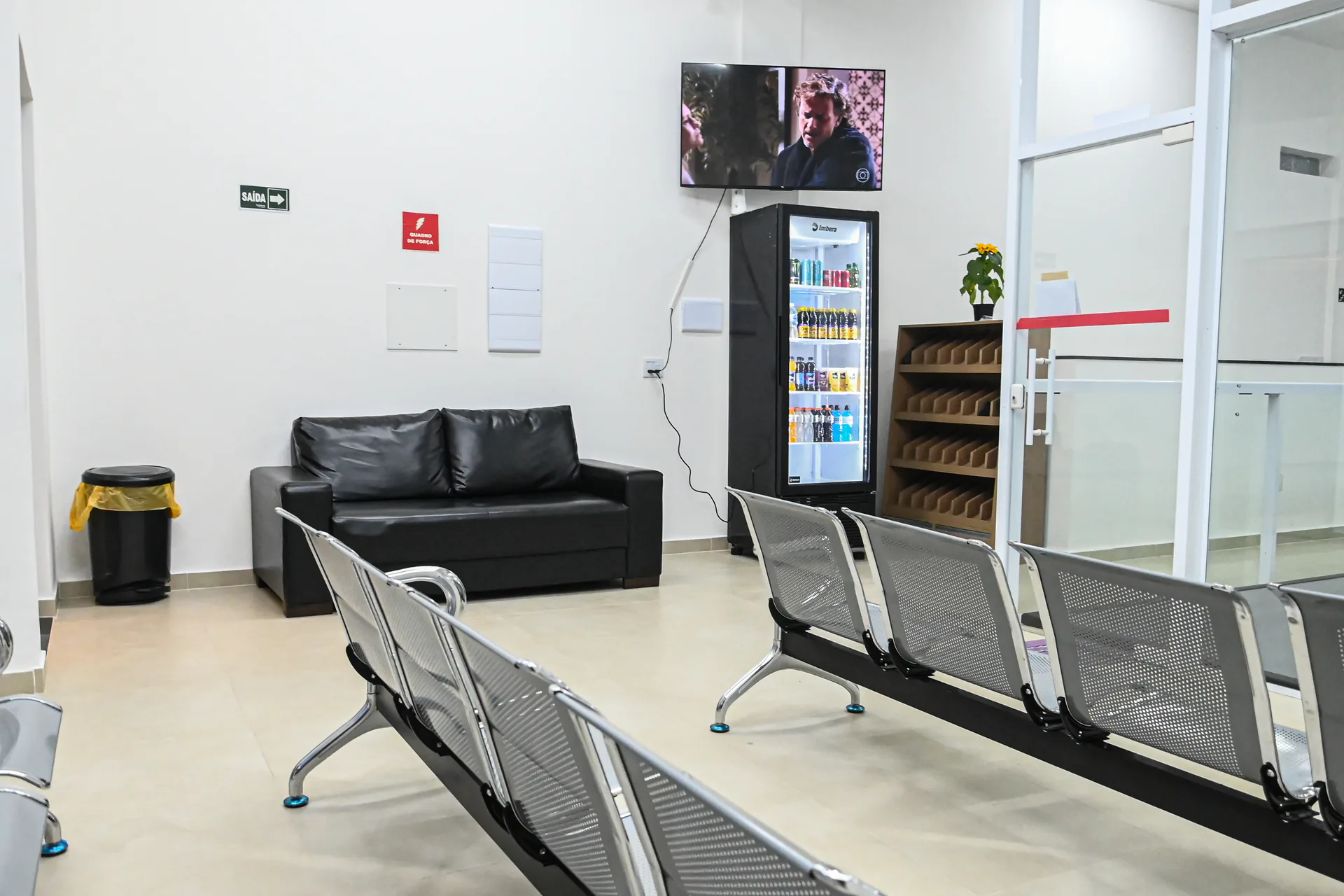 Área de espera com sofá, cadeiras e frigobar de bebidas