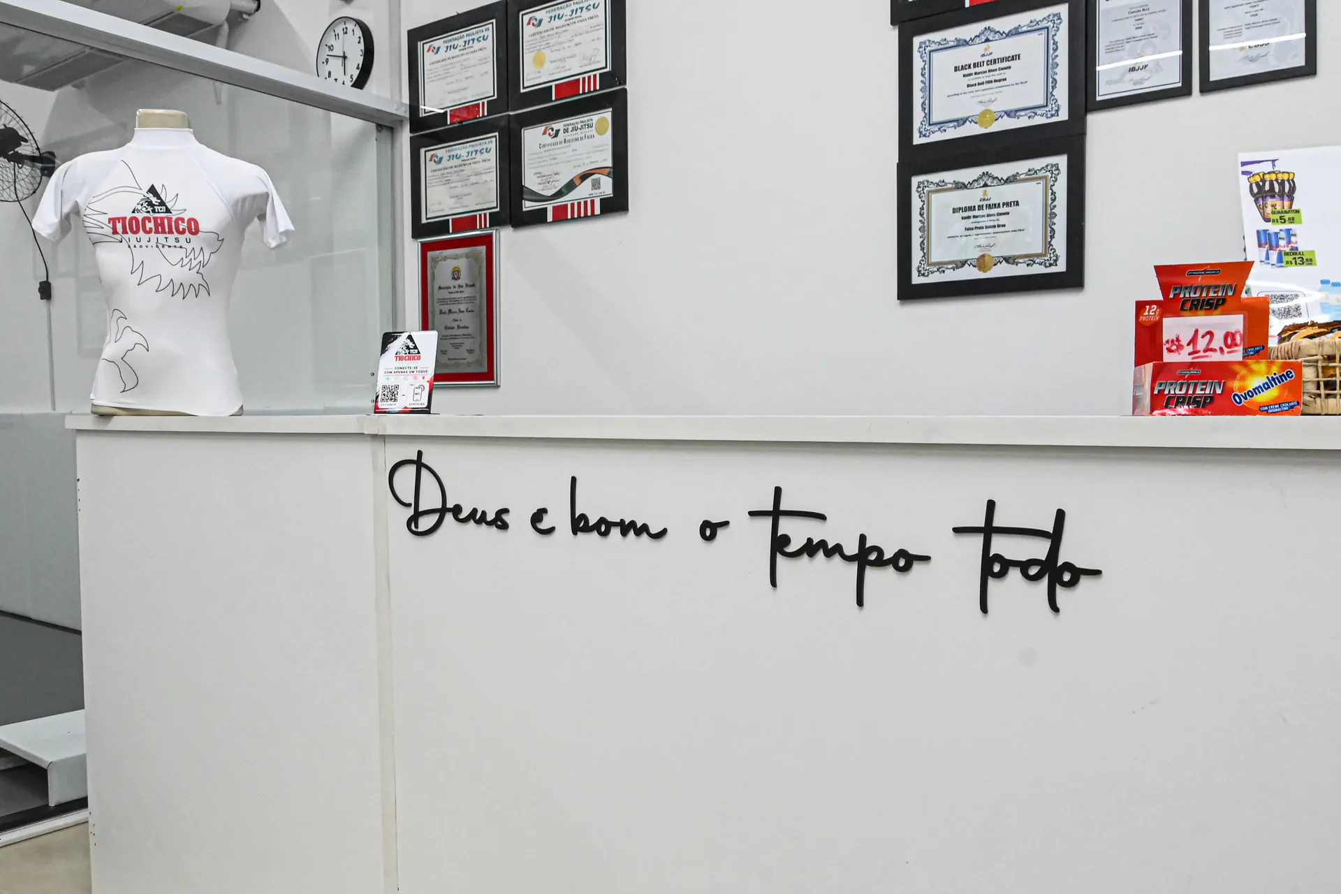 Balcão de atendimento com a frase Deus é bom o tempo todo e diplomas na parede