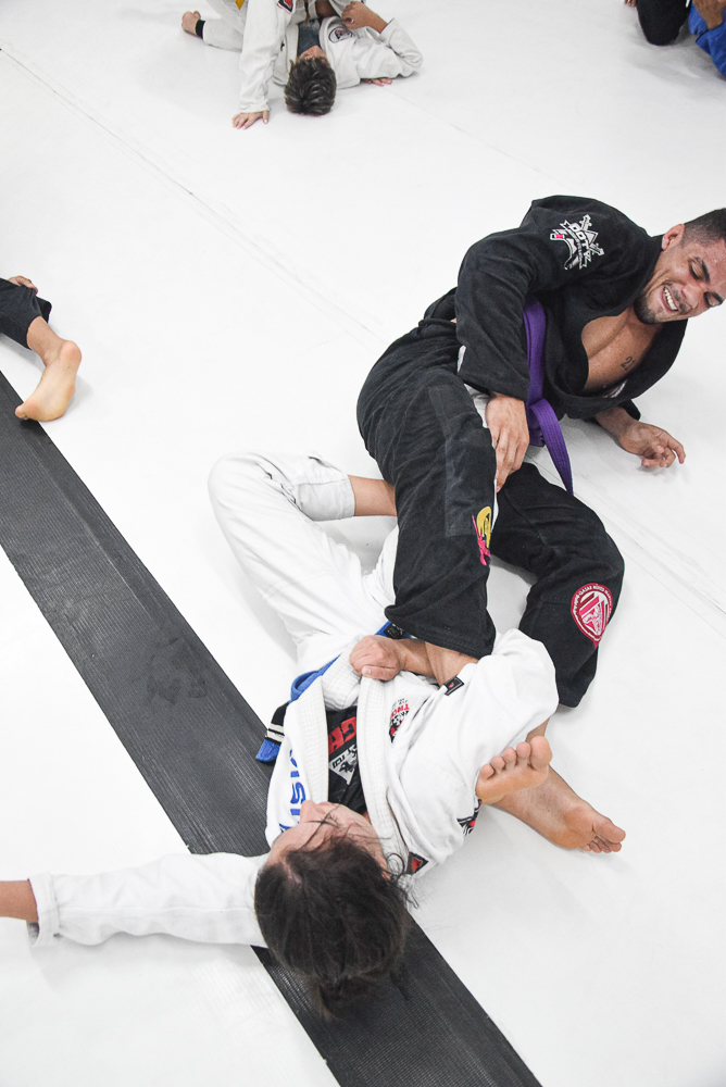 Alunos em sparring de Jiu-Jitsu no tatame da academia